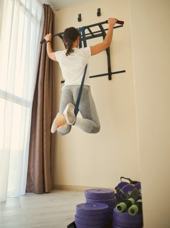 En tjej som gör chins med en pull up bar