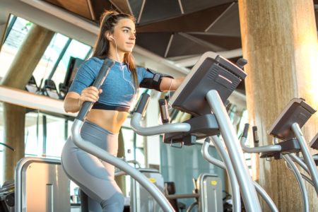 En tjej som tränar på en crosstrainer på gymmet