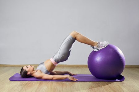 En kvinna som tränar hemma på en pilatesboll